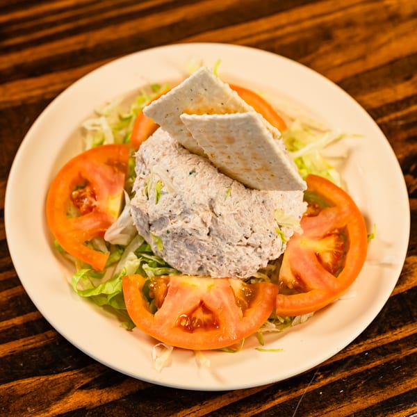 A Mediterranean tuna salad with crackers, lettuce, and tomato slices on a plate.